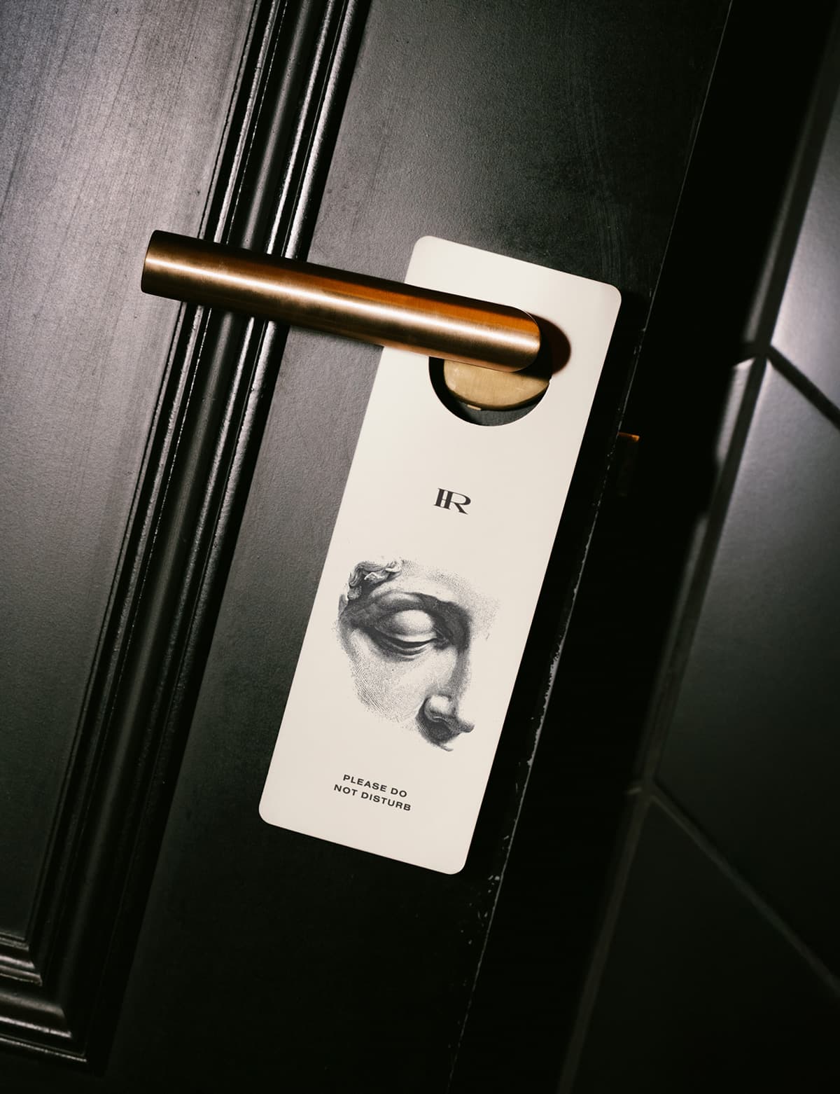 A Hotel Rossi door hanger on a dark hotel room door