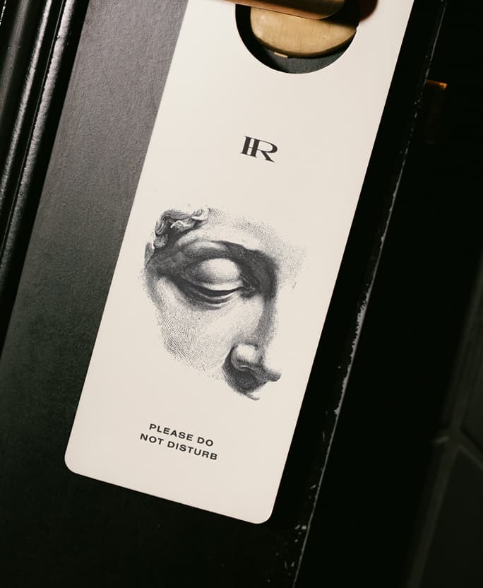 A Hotel Rossi door hanger on a dark hotel room door