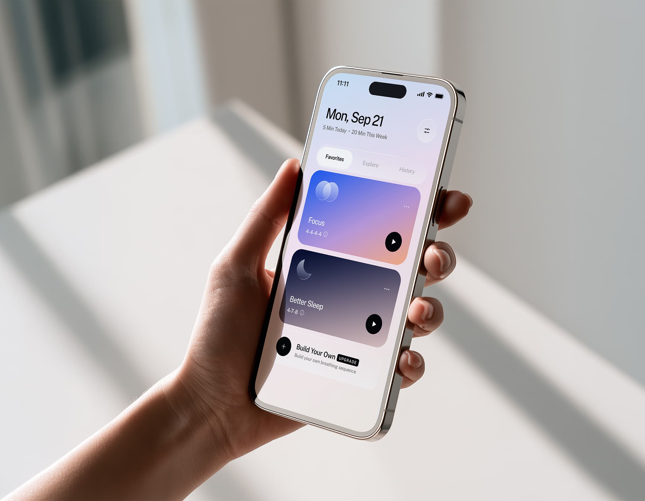 A hand holding an iPhone showing the BreathOS home screen with the Focus and Better Sleep sessions